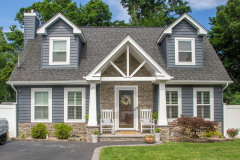 Charming two-story house with gray siding and stone accents.