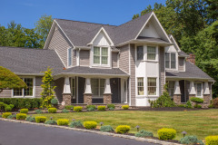 Traditional two-story house with gray siding and stone accents.