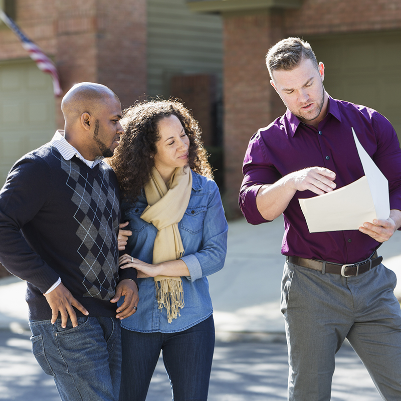 3 people outside looking at paper